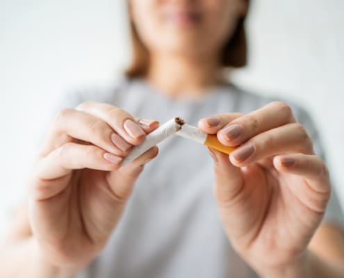 Portrait Of Beautiful Smiling Girl Holding Broken Cigarette In Hand, Happy Quitting Smoking. Smoking Concept, Quit Bad Habit Concept, Health Care Concept, No Smoking.
