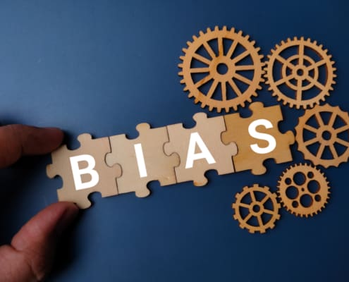 Hand Holding Wooden Puzzle With The Word BIAS On A Blue Background