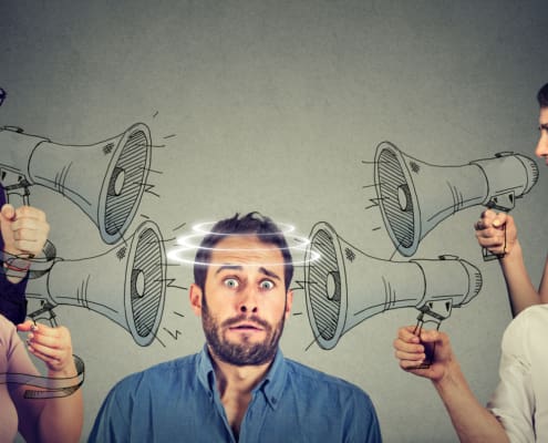 Group Of People Screaming In Megaphones At Scared Guy