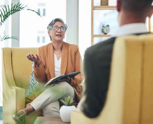 Talking, Psychologist And Man For Therapy, Advice Or Discussion Of Mental Health. Meeting, Consultation And A Female Therapist With A Patient For Counseling Support, Conversation Or Help In An Office
