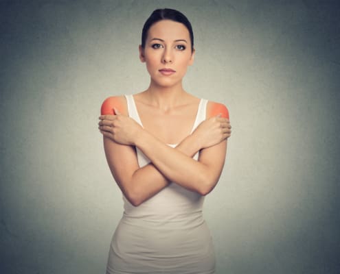 Young Woman With Bilateral Shoulder Pain Or Stiffness Colored In Red Isolated On Gray Wall Background