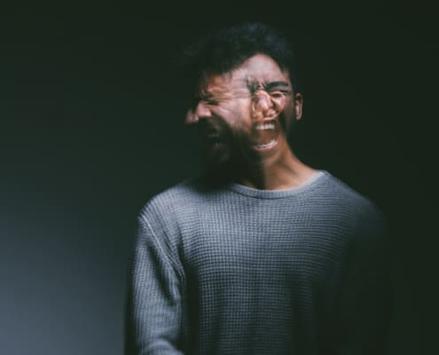 Studio Shot Of A Young Man Experiencing Mental Anguish And Screaming Against A Black Background