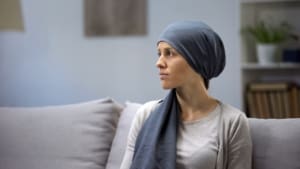 Upset Young Lady In Headscarf Lonely Sitting On Sofa In Oncologic Hospital