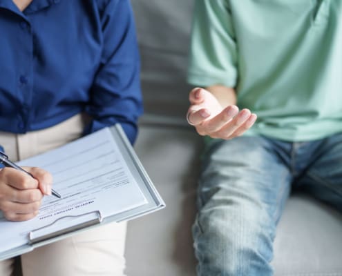 Sad Male Sitting On sofa Patient Discussing Mental Health Issues With Psychologist. depressed Asian Man Mental Health Treatment